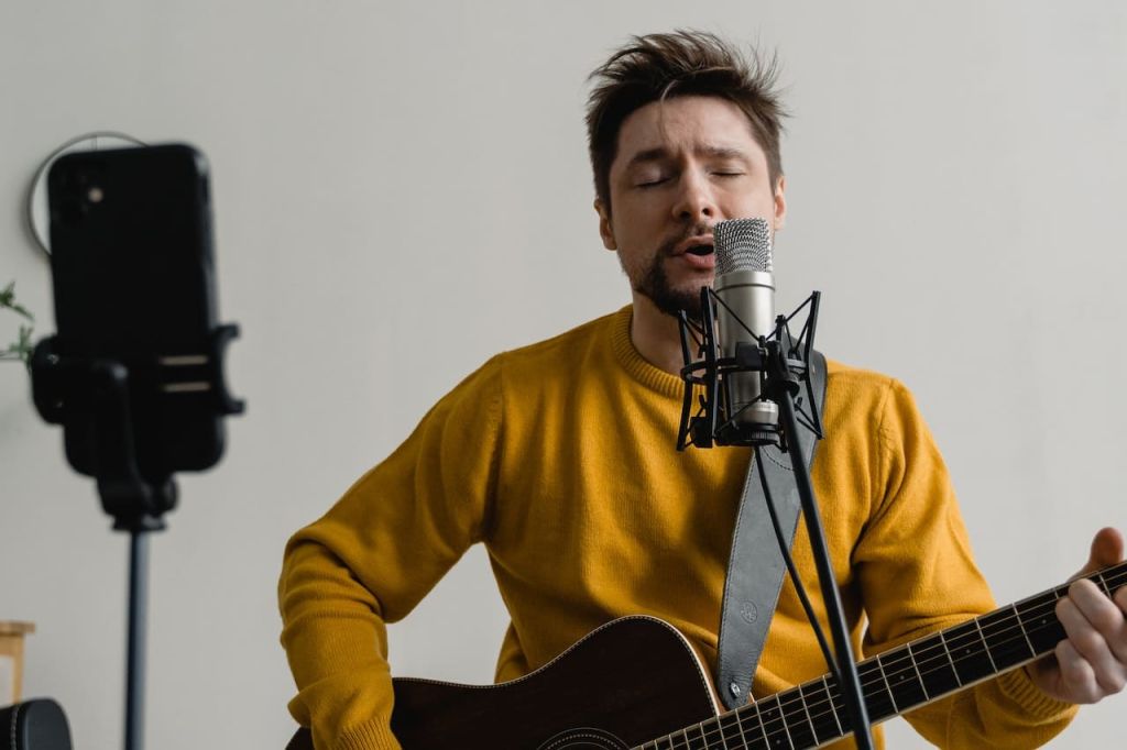 Homme qui chante dans un micro et qui joue de la guitare