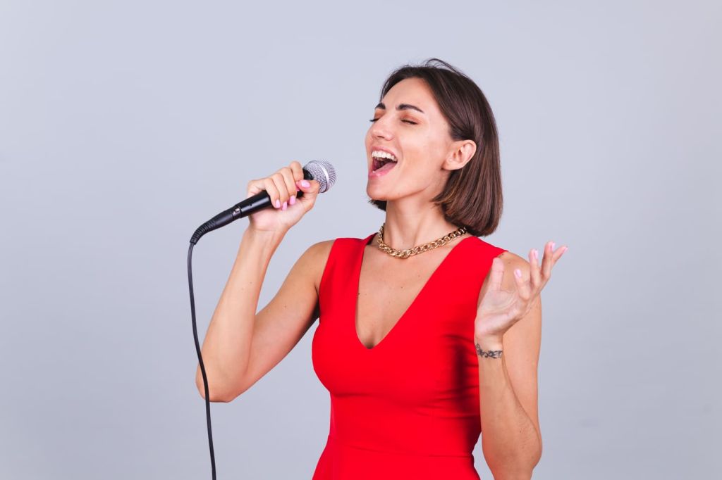 Femme en robe rouge qui chante dans un micro